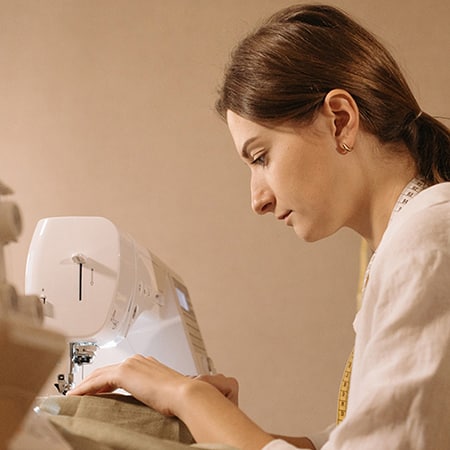 couturiere-450 Une jeune femme est entrain de coudre.