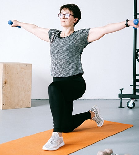 Une femme vue de dos donne un cour de stretching à une foule reproduisant ses mouvements.