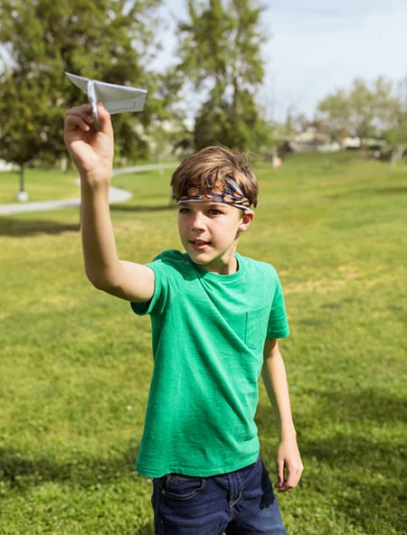 Dans un parc un enfant s'apprête à lancer un avion en papier