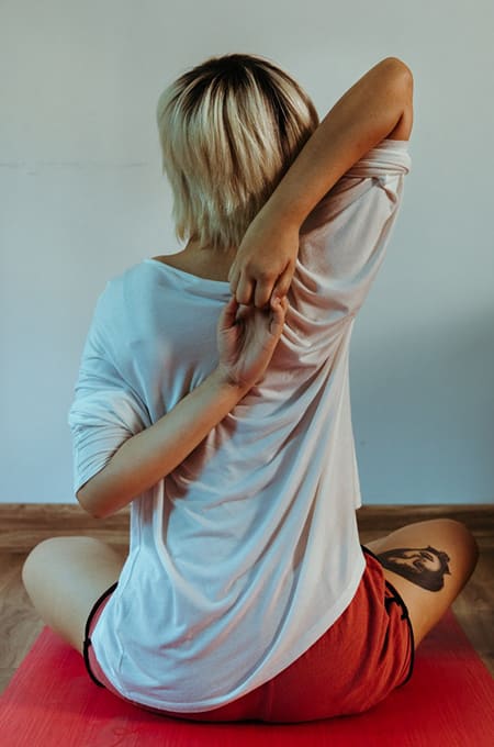 Une femme vue de dos se tient les mains et s'étire