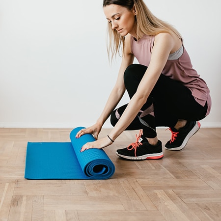 Une femme vue de dos donne un cour de stretching à une foule reproduisant ses mouvements.